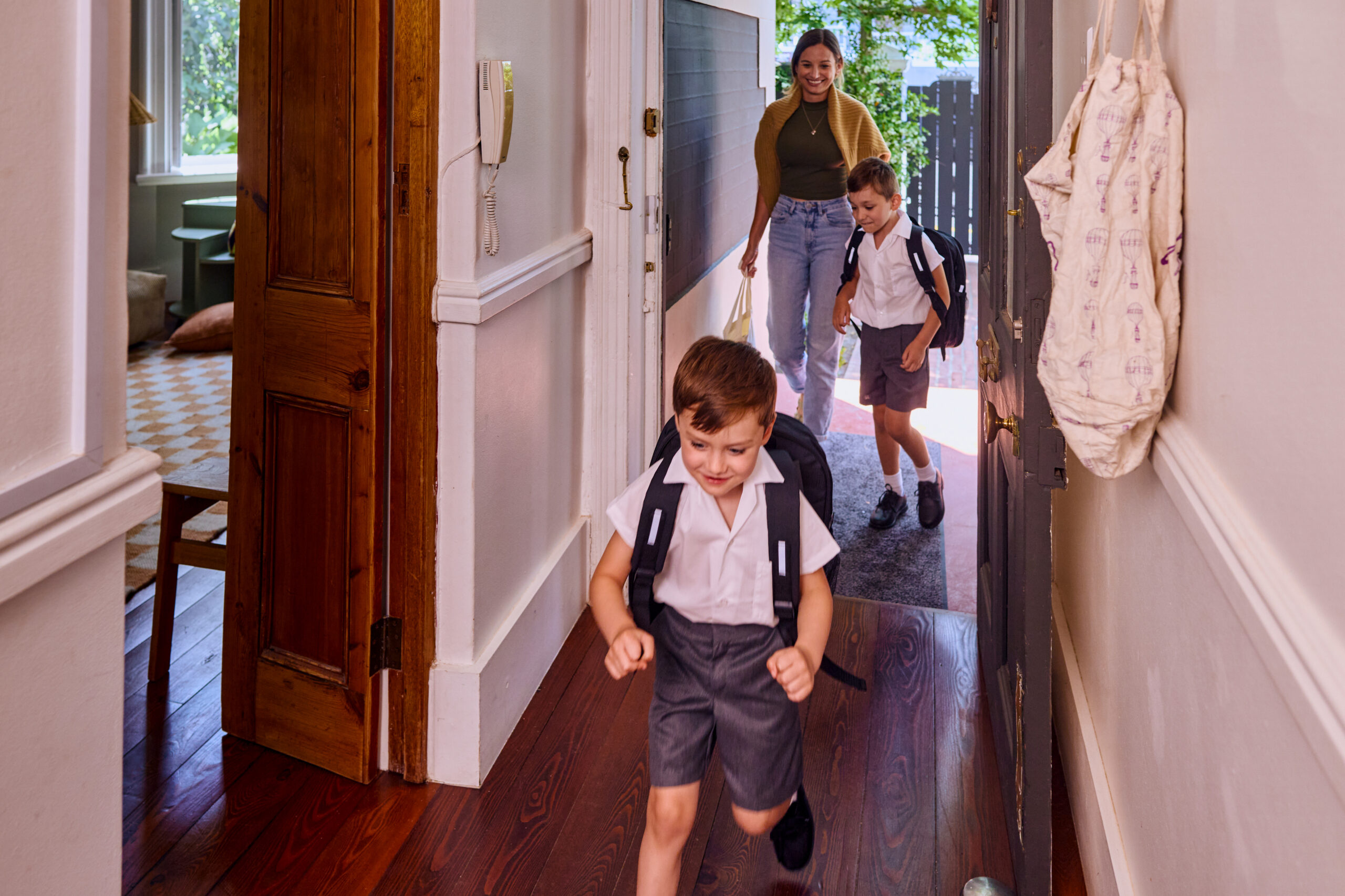 Foster carer and her two foster children leaving home in the morning, going to school, happy and smiling